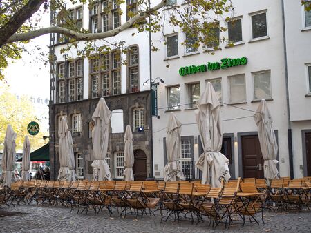 Germany, Cologne - October 2018. Sunny street, multicolored buildings, cozy cafes, city life. Open air cafe near downtownのeditorial素材
