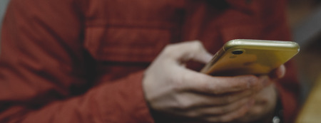 Close up of a man using mobile smart phone, orange colorの写真素材