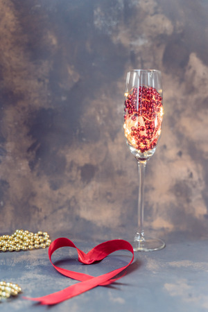 Wine glass and a red heart with pearls against dark background, valentine's day conceptの写真素材