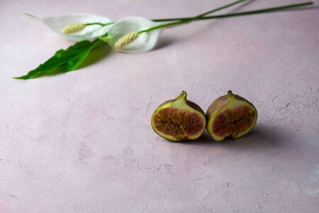 fresh whole and cut figs with some flowers on a light pink marbled background with copy space. Selected focusの写真素材