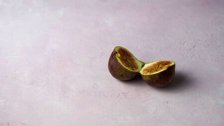 Arrangement of fresh cut figs with some flowers on a light pink marbled background with copy space....