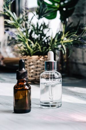 Brown, clear glasses with dropper, organic green leaves on dark background. Serum or essential oil with herbal extractの写真素材