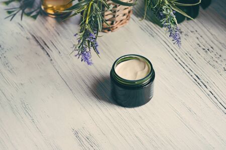 Cosmetic cream container with green herbal leaves on white backgroundの写真素材