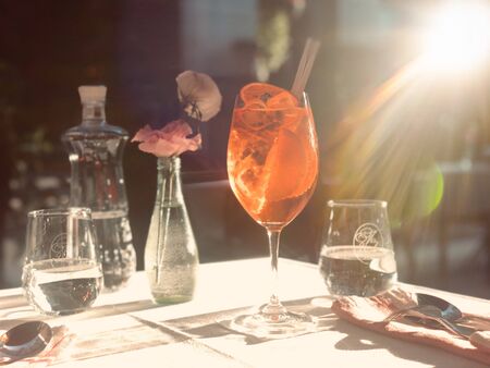 Glass of Aperol Spritz cocktail on the table in street restaurant, famous refreshing drink in sunny...