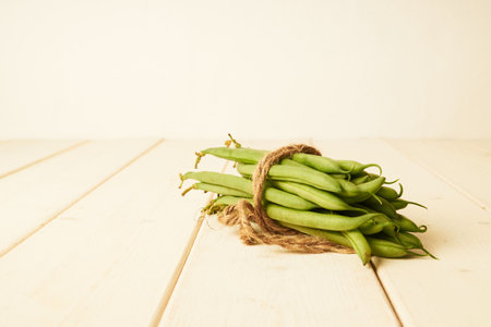 bunch of raw green beans tied up with a string on white wooden tableの写真素材
