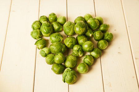 Bunch of fresh raw Brussel sprouts in heart shape on a white wood tableの写真素材