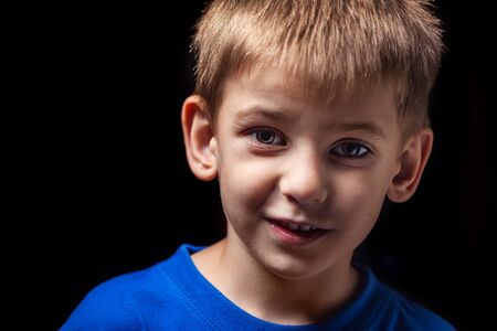 Portrait of the boy s smiling child close-up against a black backgroundの写真素材