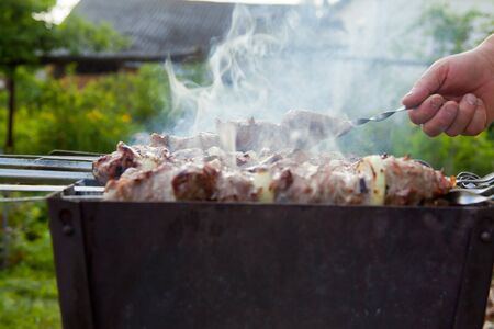 Shish kebab on the grill on the street. Smoke. Skewer in handの写真素材
