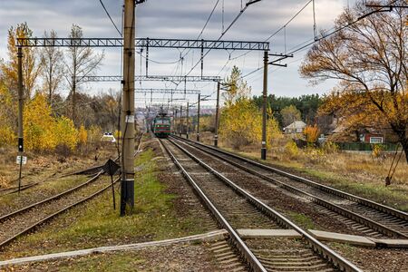 electric locomotive approaching along a railway track in the countryside, autumn landscapeの写真素材