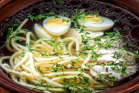 soup with chicken, spaghetti, quail eggs and herbs close-up food backgroundの写真素材