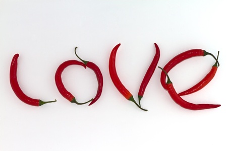 Red hot chili peppers arranged as the word LOVE on white backgroundの写真素材