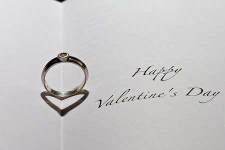 Ring casting heart shadow in book with the sentence "Happy Valentine's Day"の写真素材