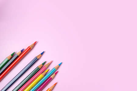 Color pencils on light pink background, top right view with space for text. Back to school concept. Flat lay stationery mockup. Bright colorsの写真素材