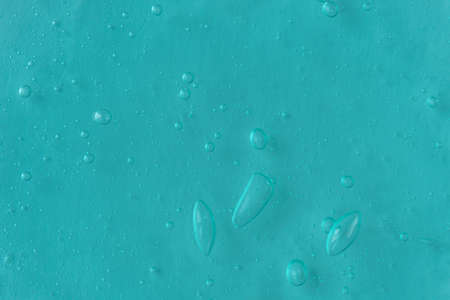 Texture of transparent mint antiseptic gel with air bubbles on light blue monochrome background....