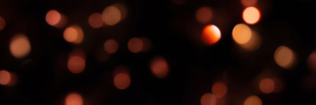 Banner of defocused bokeh lights on black background, an abstract naturally blurred backdrop for Christmas or birthday party. Festive light texture. Red garland in blur. Overlay effect for designの写真素材