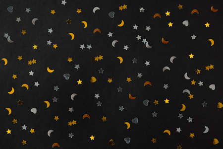 Silver and golden stars, hearts and moons on black decorating paper background. Backdrop for postcards or banners. Luxury new year 2022 decoration packaging. Merry xmas or birthday conceptの写真素材