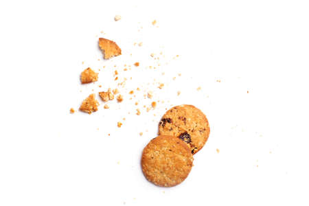 Scattered crumbs of vanilla chip butter cookies isolated on white background. Close-up view of brown...