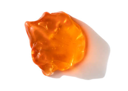 Orange cosmetics or antiseptic gel, cleaner or serum drop isolated on white background . Colorful amber slime with air bubbles in the sunlight. High contrast trendy photo. Health protection conceptの写真素材