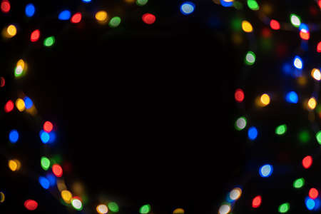 Defocused bokeh lights on black background, an abstract naturally blurred backdrop for Christmas eve or birthday party. Festive light texture. Colorful garland in blur. Overlay effect for designの写真素材