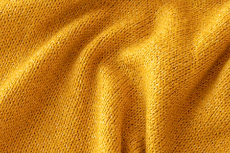 Soft knitted yellow sweater texture closeup. Light orange abstract background. Trendy soft...