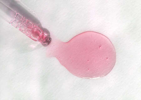 Pipette with pink fluid hyaluronic acid on white background. Cosmetics and healthcare concept. Dose...
