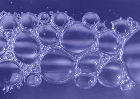 Air bubbles in violet blue beauty product bottle. Close-up. Liquid gel or herbs oil in glass...