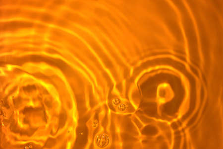 The texture of circles on water. Drops of liquid on orange background. Perfect backdrop for design projects. Summer holidays, laboratory analysis and research conceptの写真素材