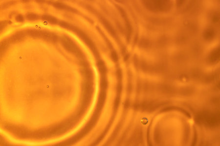 The texture of circles on water. Drops of liquid on orange background. Perfect backdrop for design projects. Summer holidays, laboratory analysis and research conceptの写真素材