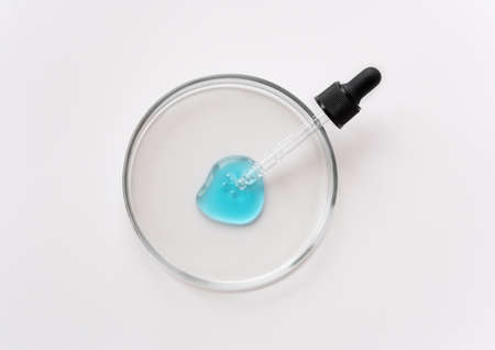 Laboratory glass petri with pipette and blue drop of serum, oil, beauty product. Natural medicine, cosmetic research, bio science. Concept of skincare and analysis. Dermatology. Flat lay, top viewの写真素材