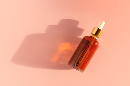 Transparent amber green glass dropper bottles with liquid inside on beige background in the sunlight. Pipette with fluid hyaluronic acid, serum, retinol. Cosmetics, healthcare, beautyの写真素材