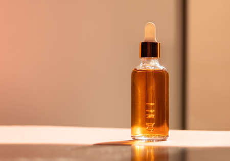 Cosmetic glass dropper bottle with oil, serum or fruit peeling in the sunlight. Natural beauty product presentation on natural background. Front view. Web banner. Mockup concept for cosmetic productsの写真素材
