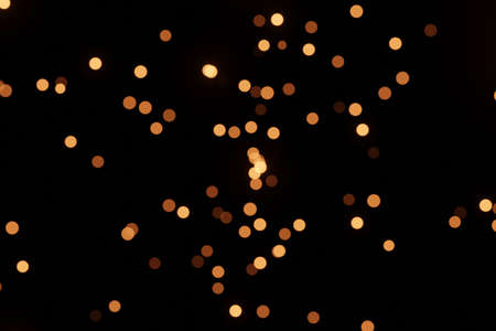 Defocused bokeh lights on black background, an abstract naturally blurred backdrop for Christmas eve...