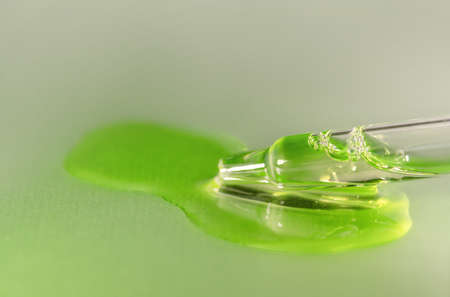 Pipette with fluid hyaluronic acid on gray background. Cosmetics and healthcare concept closeup. Dose of serum, retinol with air bubbles. Flat lay. Luxury beauty product presentation, macroの写真素材