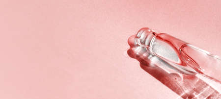 Pipette with fluid hyaluronic acid on pink background. Cosmetics and healthcare concept closeup. Dose of serum, retinol with air bubbles. Flatlay. Luxury beauty product presentation, macro. Web Bannerの写真素材