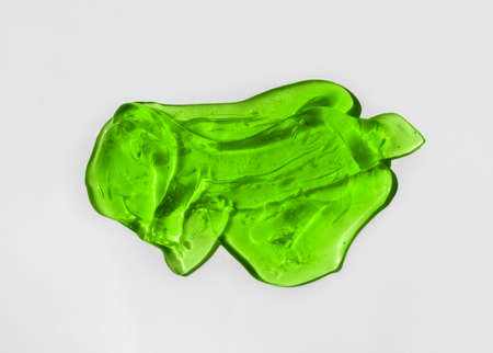 Green cosmetics gel, serum or peeling drop on white background. Colorful warm yellow slime with air bubbles in the sunlight. High contrast trendy photo. Health protection and self-care conceptの写真素材