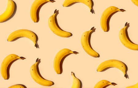 Yellow bananas pattern on a trendy beige background. Summer freshness, natural snack, organic. Healthy eating, raw food, vegan vitamins food concept. Bright abstract backdrop or wallpaperの写真素材