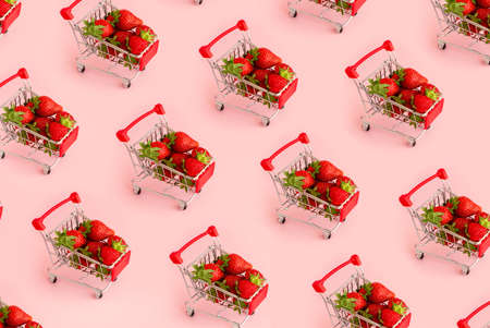 Pattern of fresh red strawberry in shopping cart on pink background. Online shopping and Valentines...