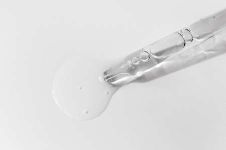 Closeup of pipette with serum, hyaluronic acid on white background. Cosmetics and healthcare...