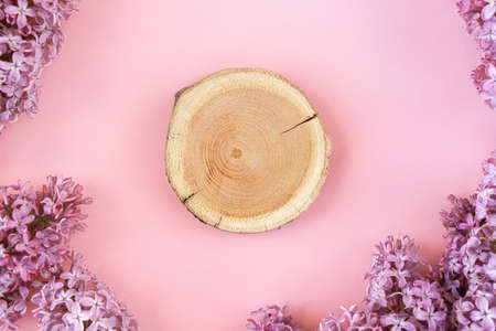 Woodcut lying on a trendy pink background with lilac flowers making a frame. A wooden platform for...