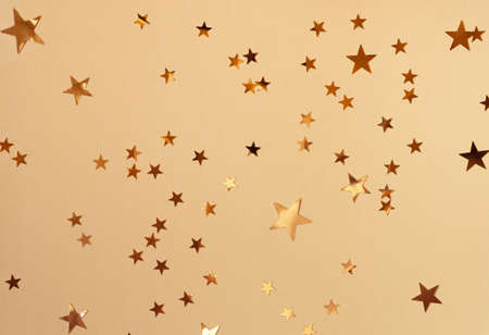 Golden stars glittering confetti on yellow background. Trendy festive holiday backdrop. Many...