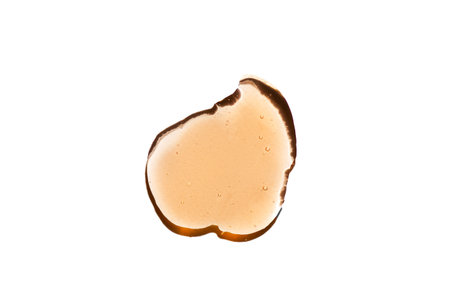 Orange cosmetics gel, serum or peeling drop isolated on white background. Oily slime with air bubbles in the sunlight. High contrast trendy beauty pattern. Health protection and self-care concept.の写真素材