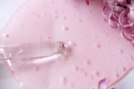 Closeup of pipette with serum, oil, gel with lilac flowers on white background. Skin care, natural beauty products presentation concept. Macro. Romantic floral composition. Front view, high angle shotの写真素材