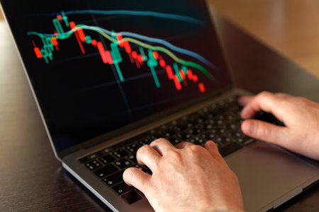Male hands monitoring stock market numbers and graph on laptop. Investment analysis, trading...