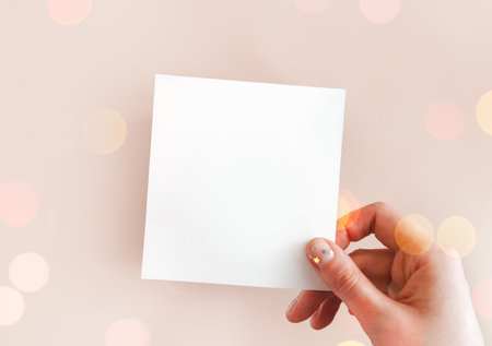 Banner of female hand with festive minimalistic natural manicure holding white piece of paper for notes with space for text. Concept of creativity, holiday wish, plans for future, art. Copy spaceの写真素材