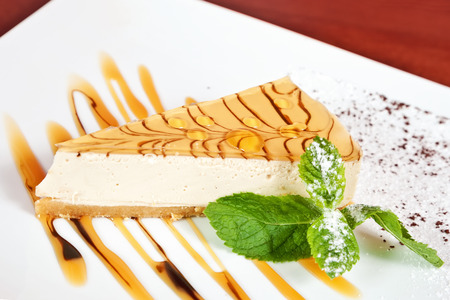 Cheesecake with mint twig, powdered sugar and caramelの写真素材
