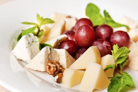 Assorted cheese plate with grape, walnuts and mintの写真素材
