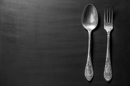 Black and white image of old fork and spoon over dark backgroundの写真素材