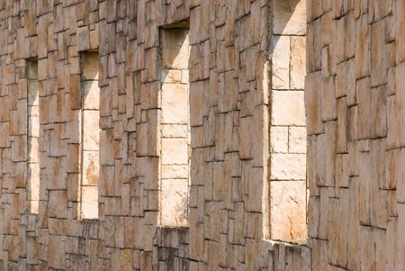 Stone wall with windows on it. Brick wall with sunshine.