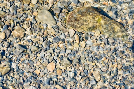 In the river, pebbles under water with reflecting light