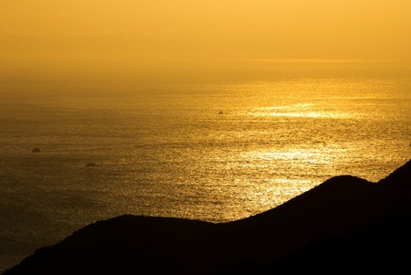Golden sunshine on the sea where fish boats is going through. The sea with light fog in distant